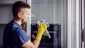 man cleaning window inside house